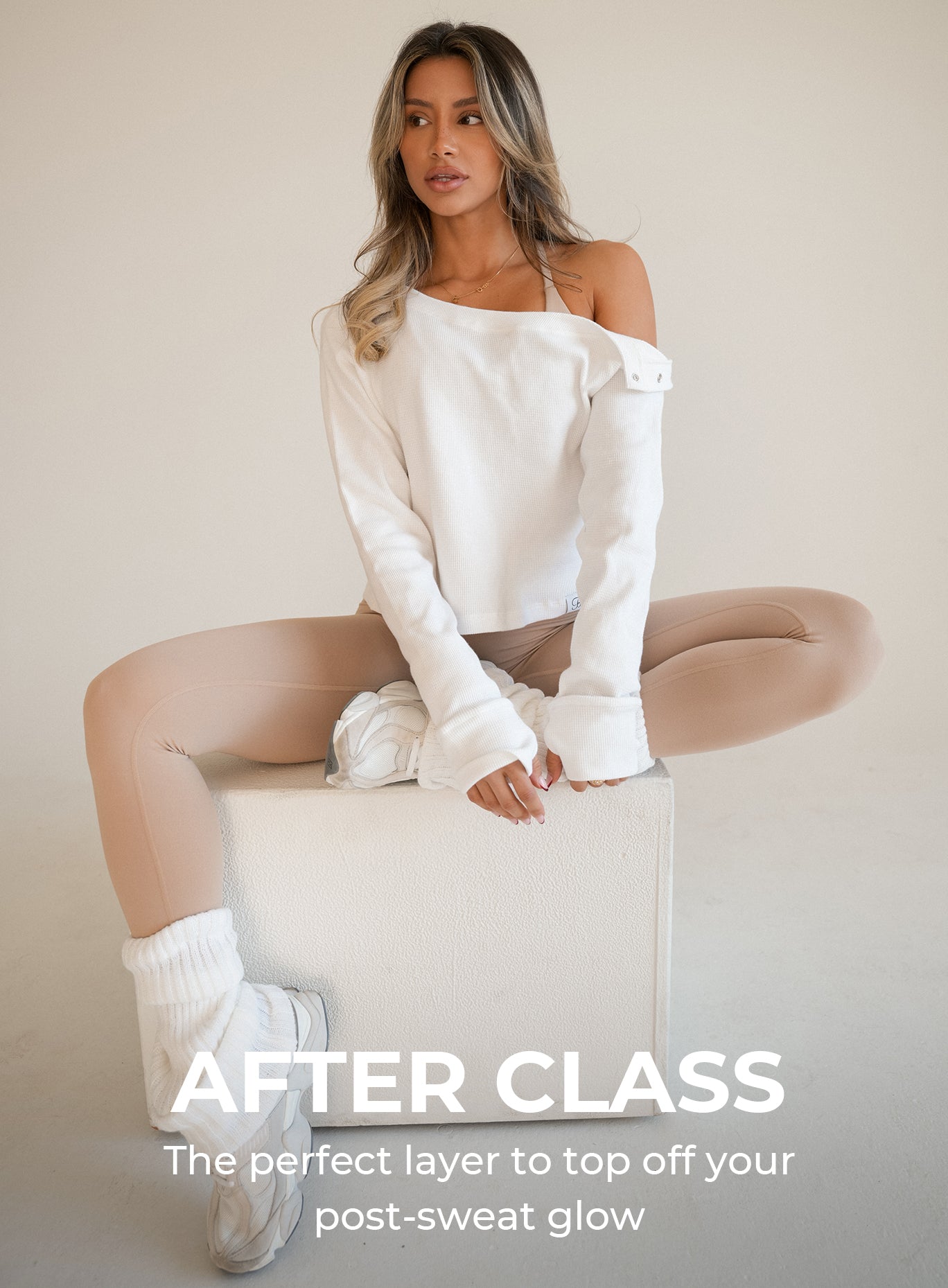 front view of a model sitting on top of a box wearing the Allure Pullover in white color